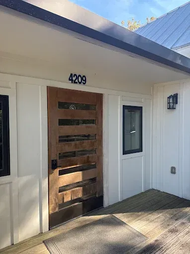 Modern white building entrance with address 4209 above a wooden door.