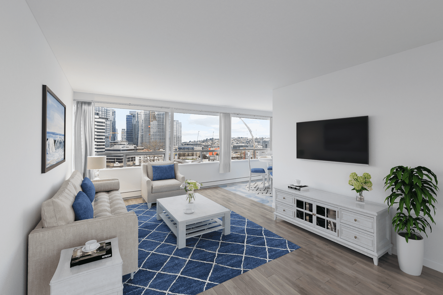 Living room with city view, blue rug, white furniture, TV on wall, and a plant.