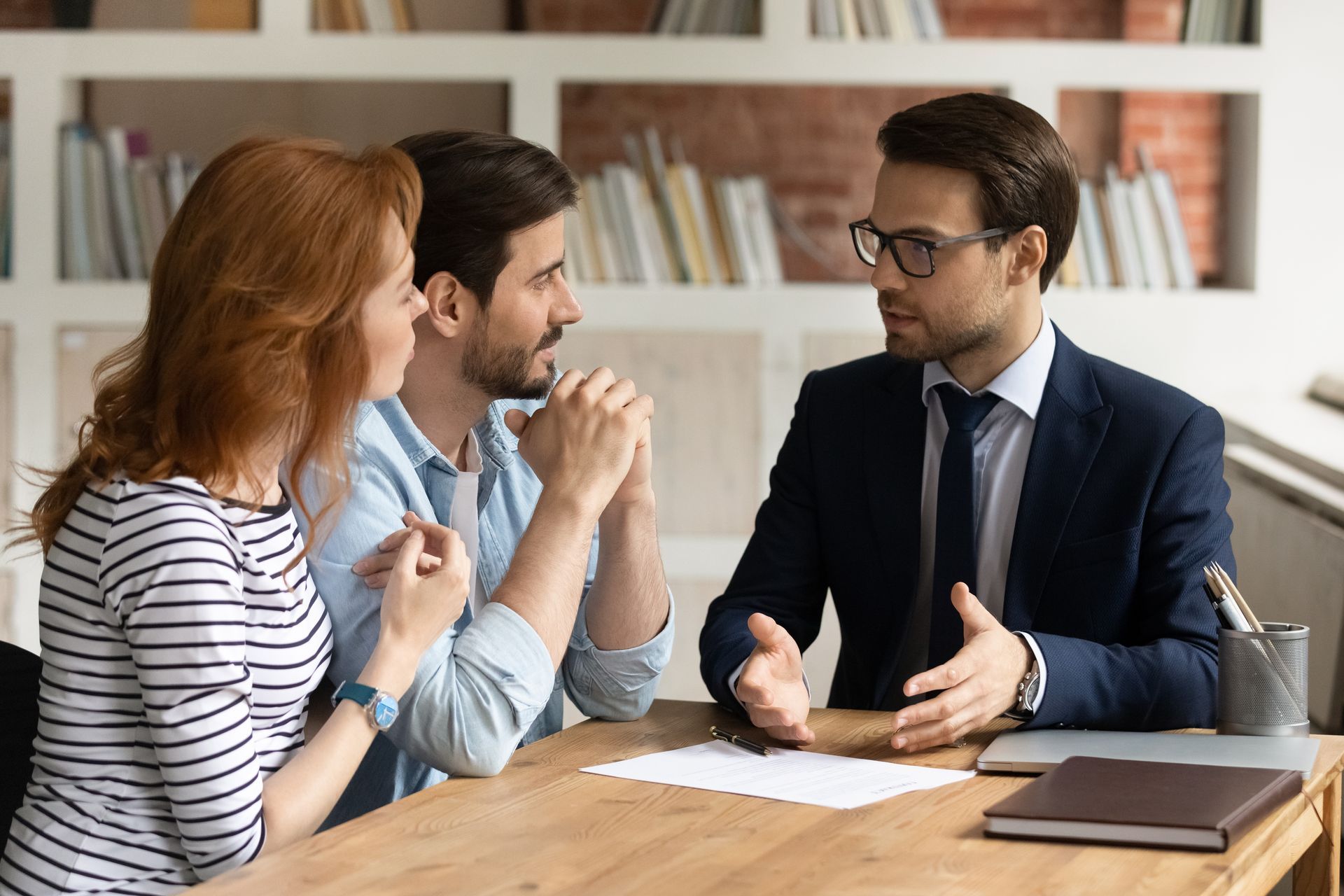 An attorney sitting at a desk and talking with a man and a woman