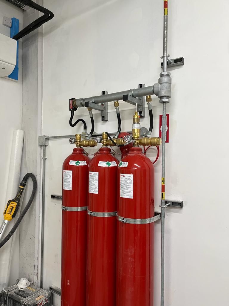 Three red fire extinguishers are hanging on a wall in a room.