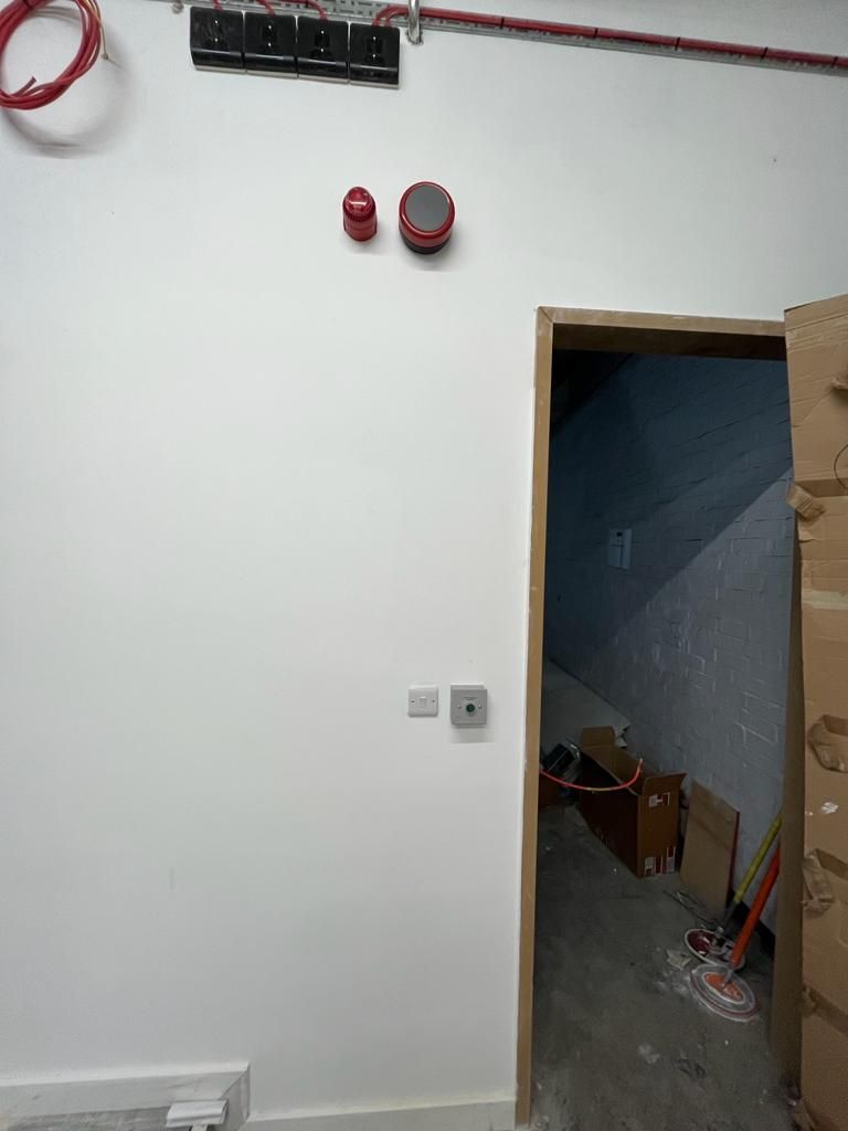 A white wall with a door and boxes on the floor