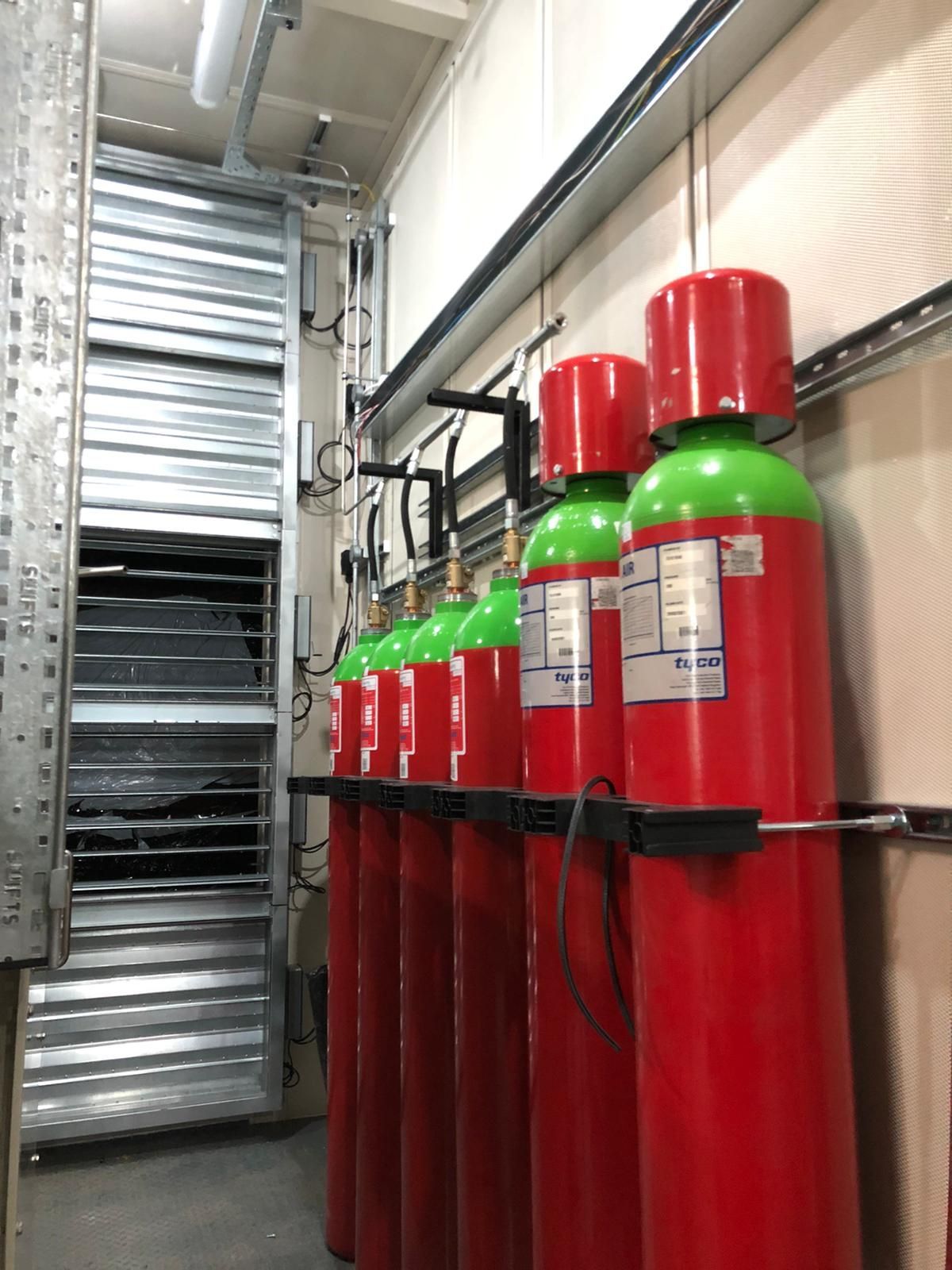 A row of red gas cylinders are lined up in a room.