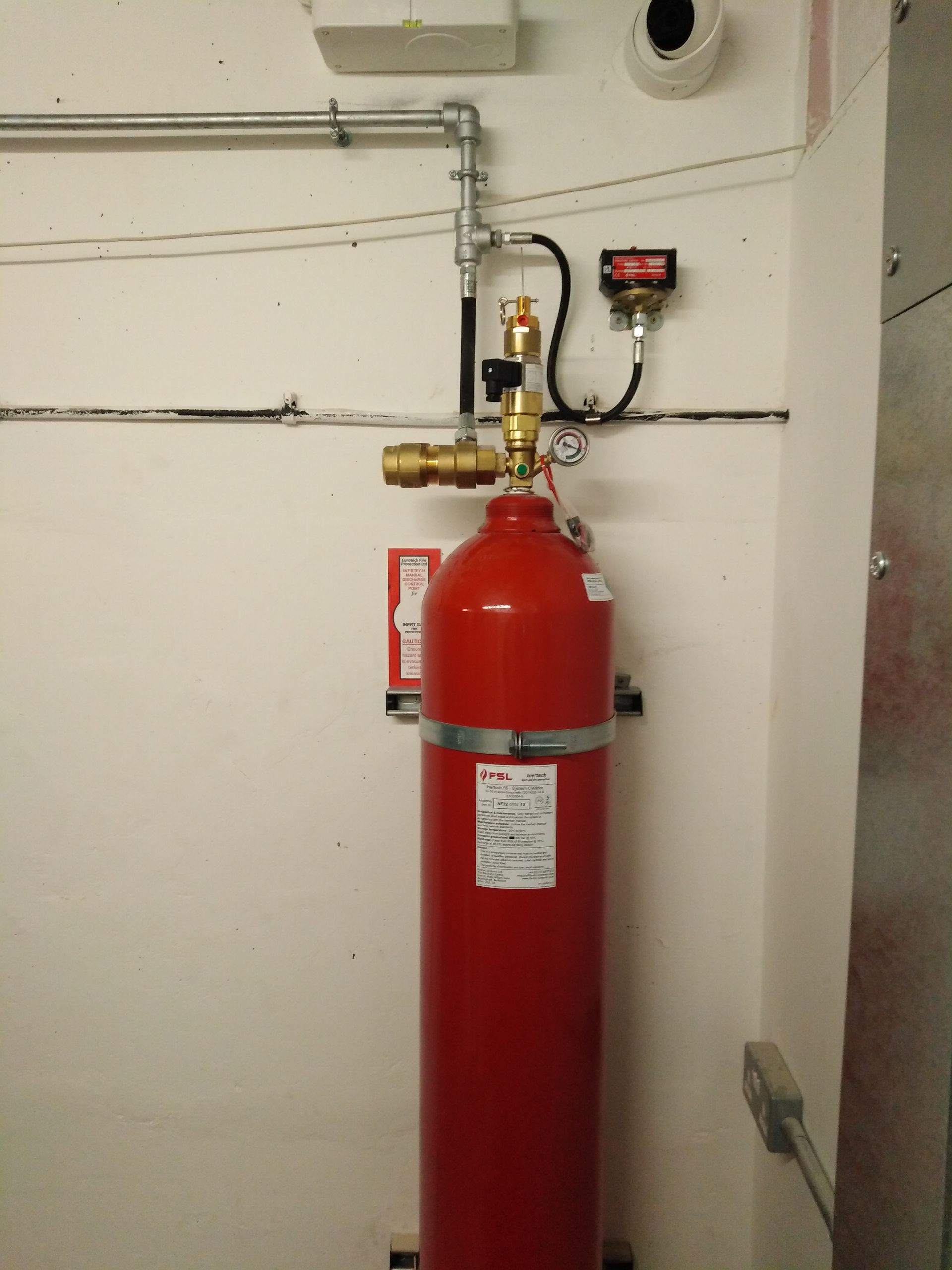 A red fire extinguisher is attached to a white wall