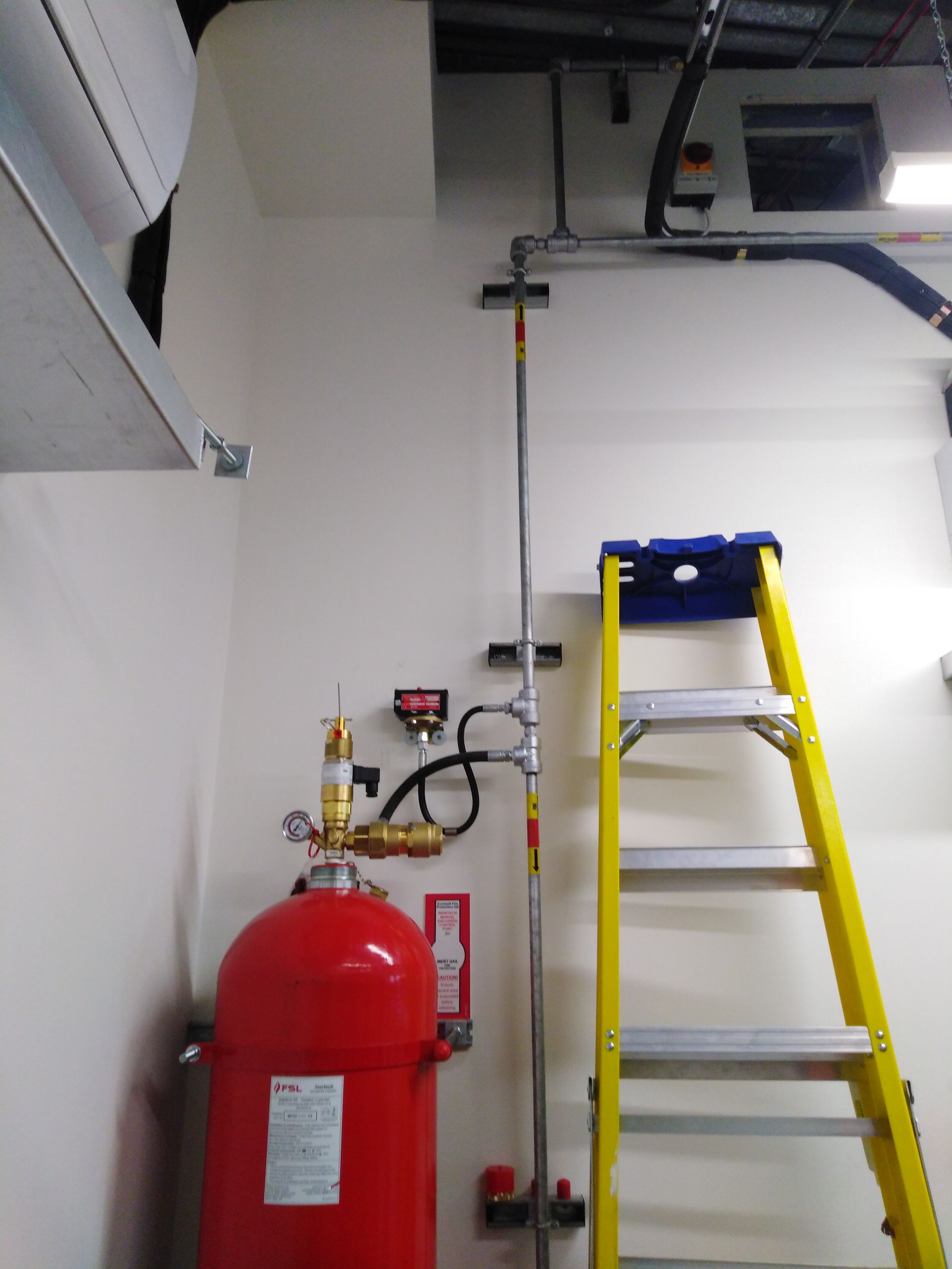 A ladder is leaning against a wall next to a fire extinguisher