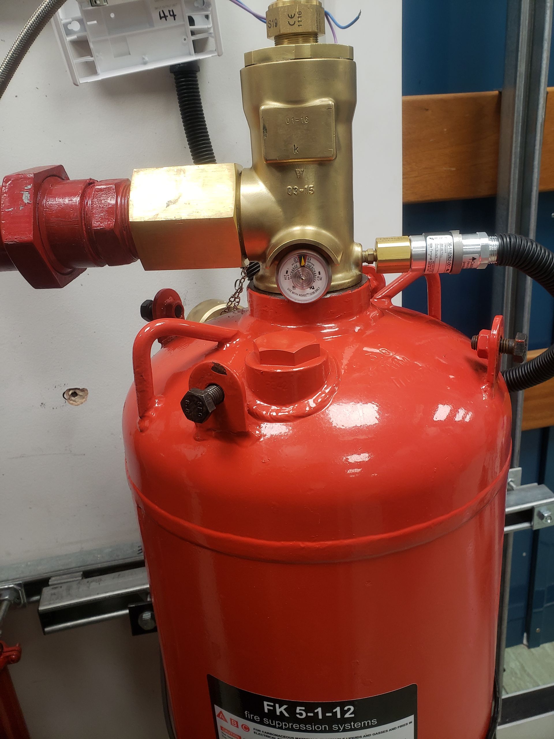 A red fire extinguisher with a gauge attached to it