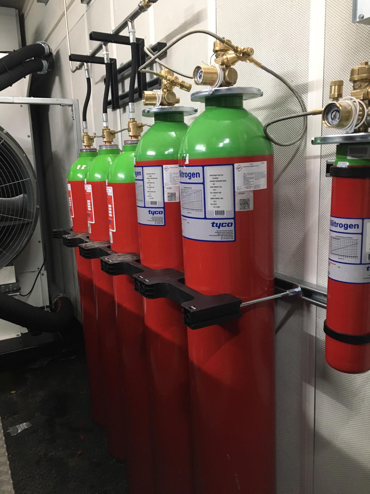 A row of red and green gas cylinders hanging on a wall.