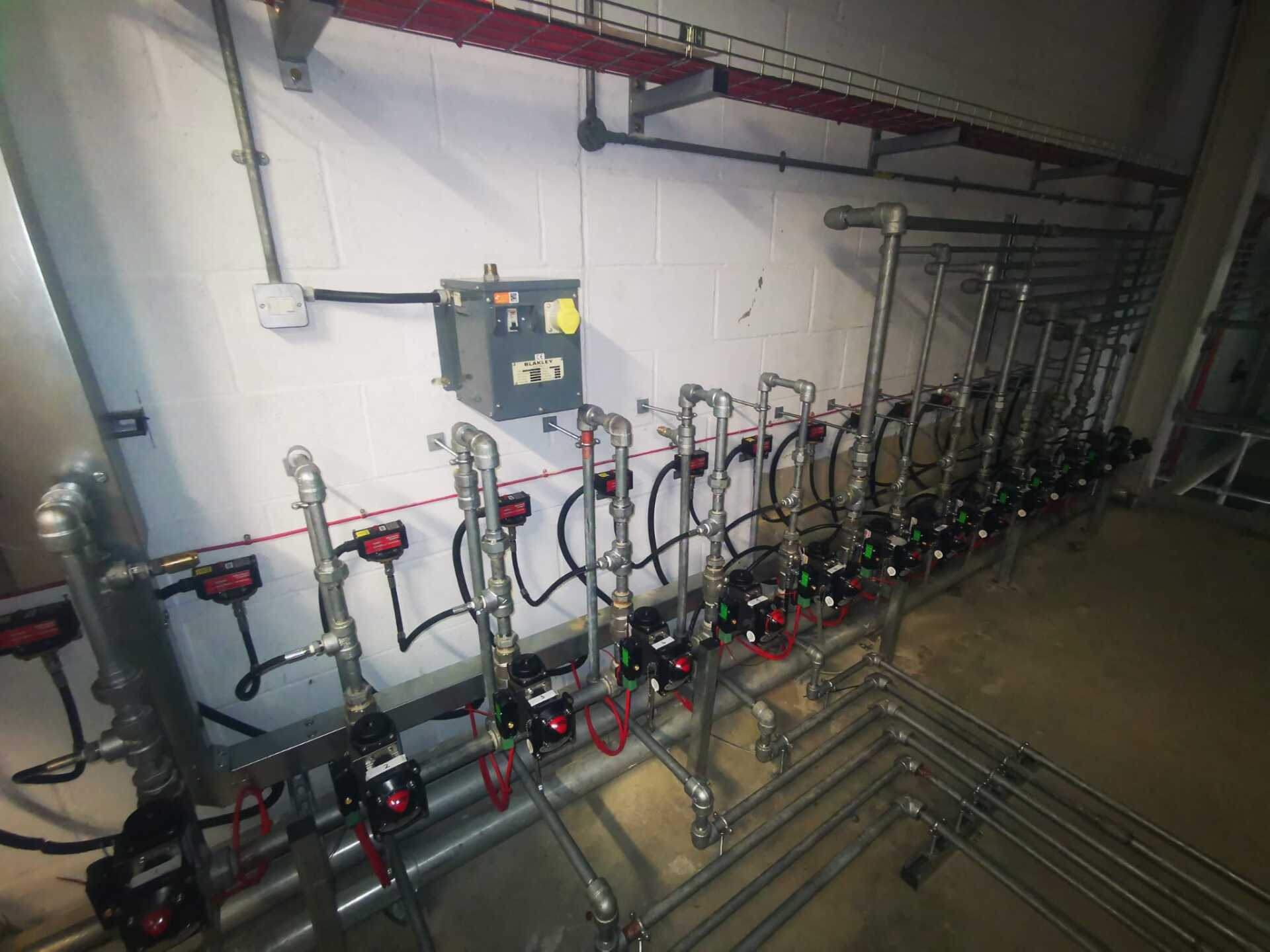 A room with a lot of pipes and valves on the wall.