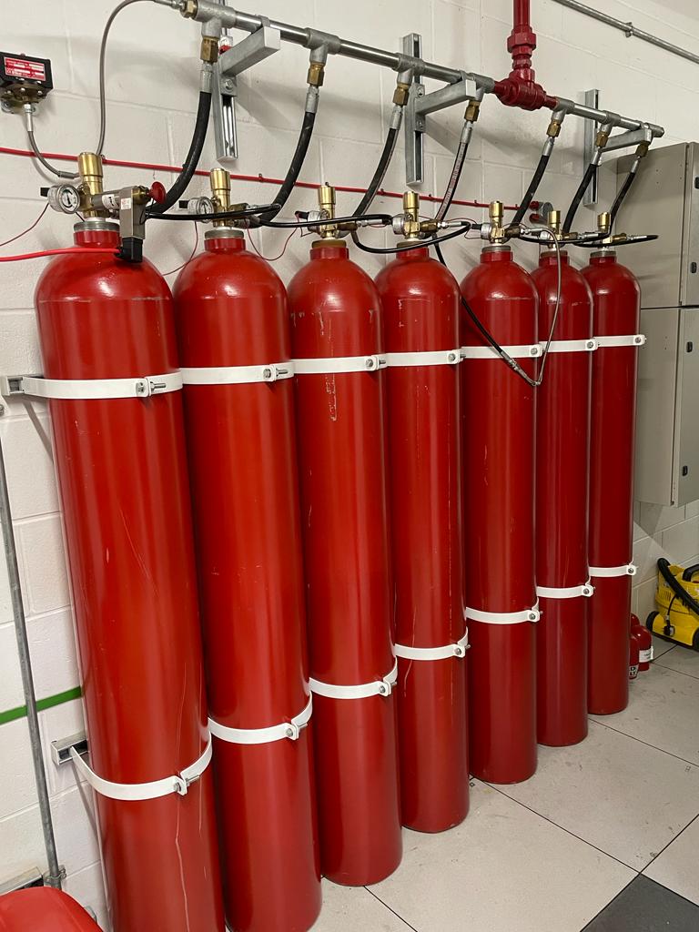 A row of red gas cylinders are lined up in a room.
