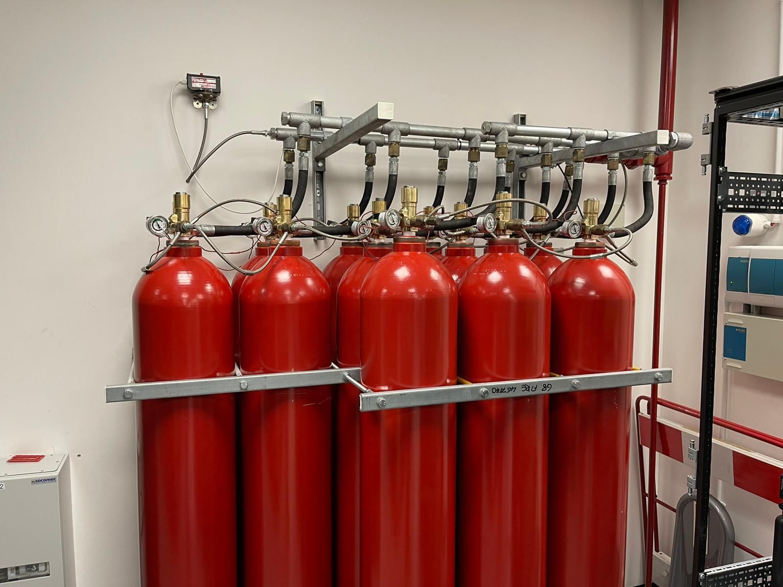 A row of red gas cylinders are hanging on a wall.