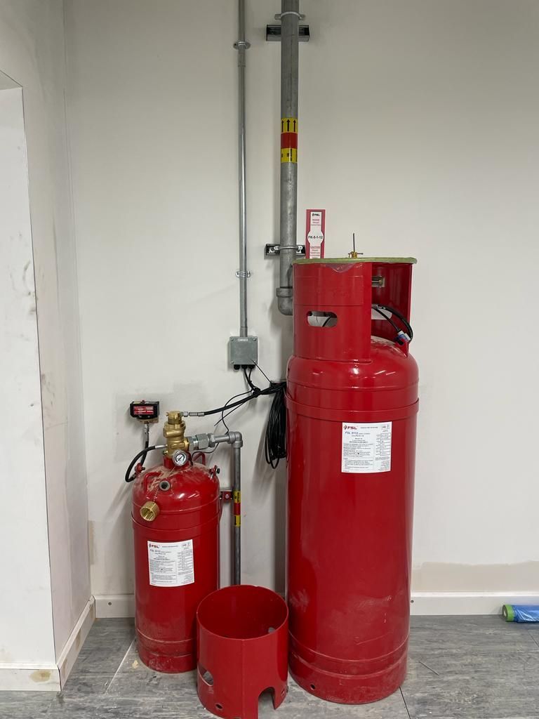 Two red gas cylinders are sitting next to each other in a room.