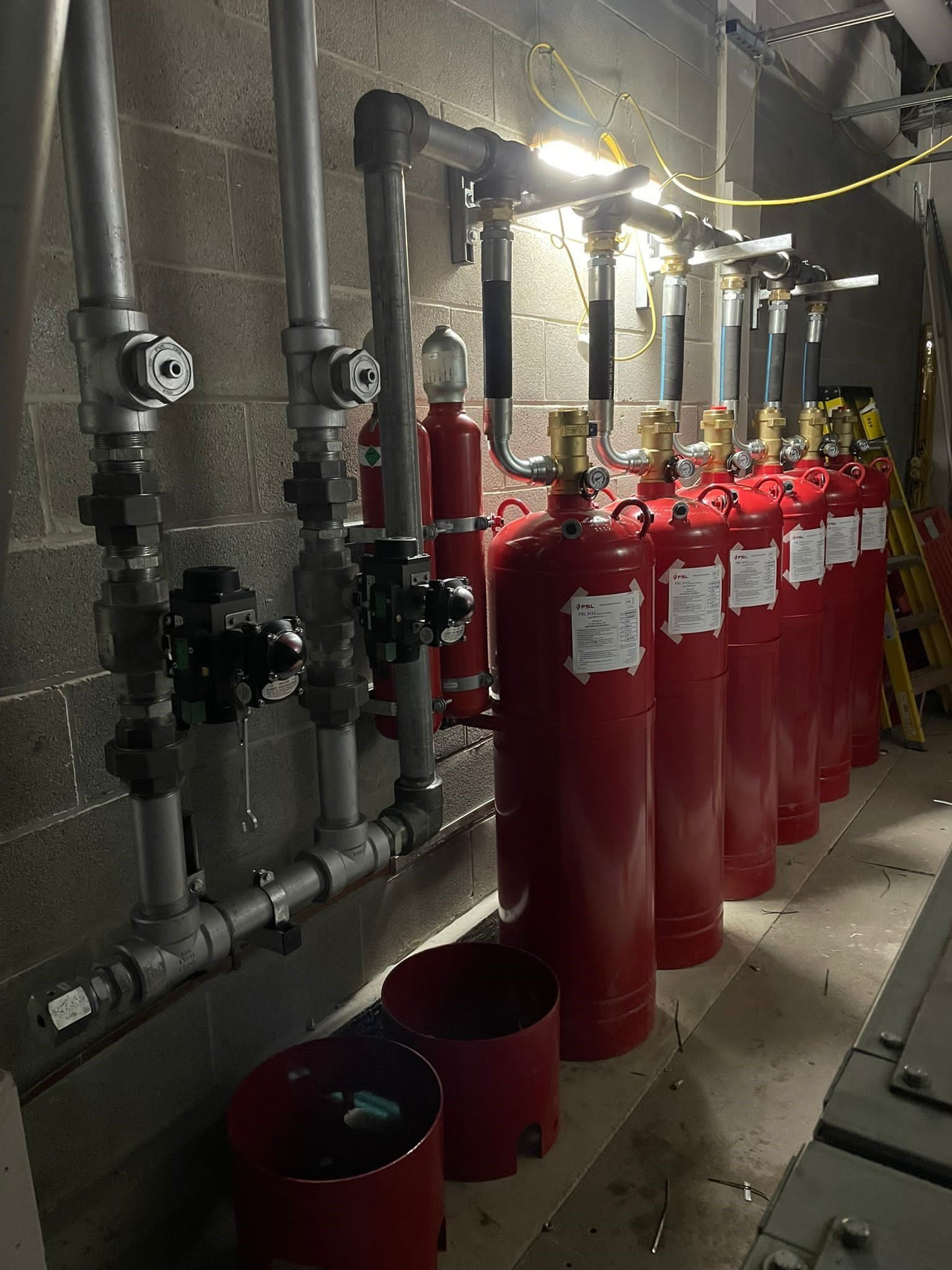 A row of red fire extinguishers are lined up next to each other in a room.