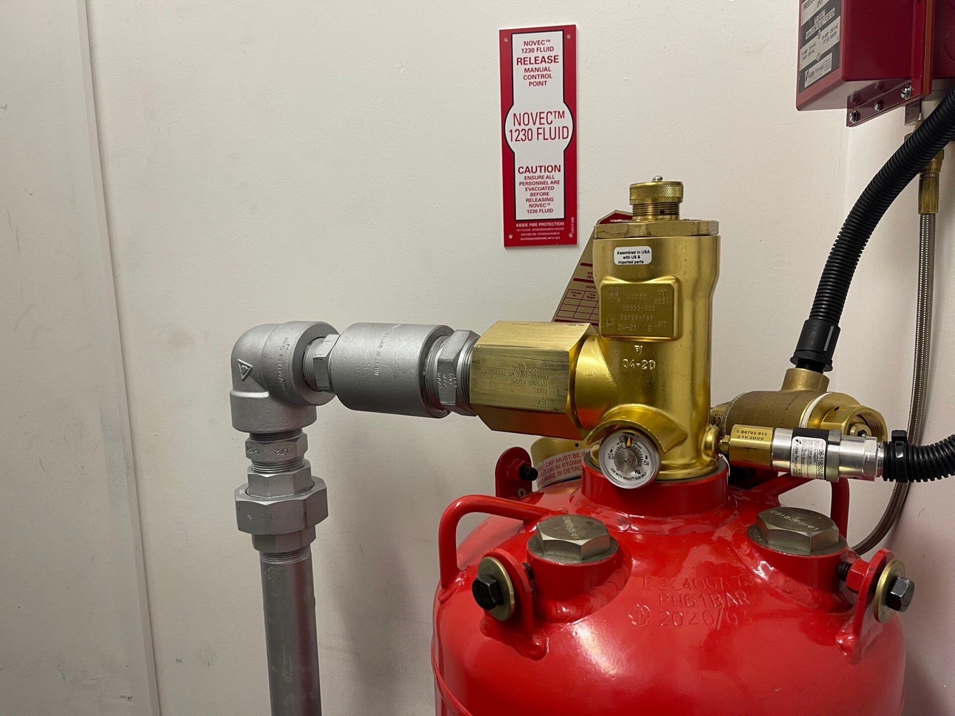 A red fire extinguisher is attached to a metal pipe.