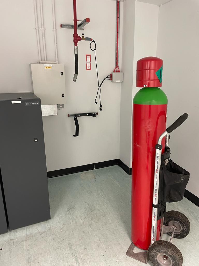 A red gas cylinder is sitting on a cart in a room.