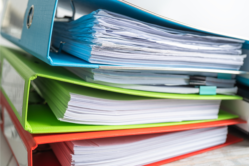 A stack of colorful binders filled with papers on a table.