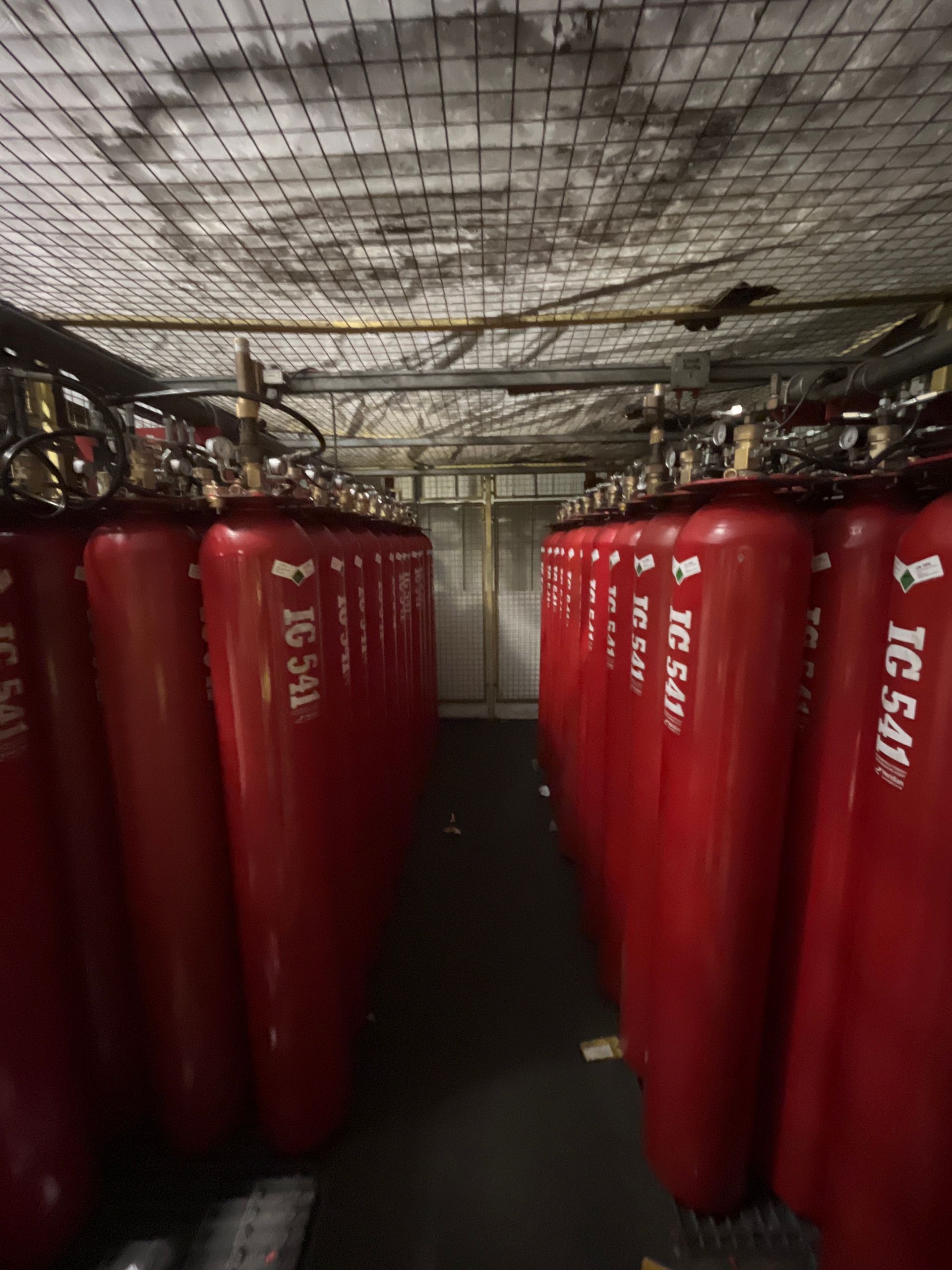 A row of red gas cylinders are lined up in a room.
