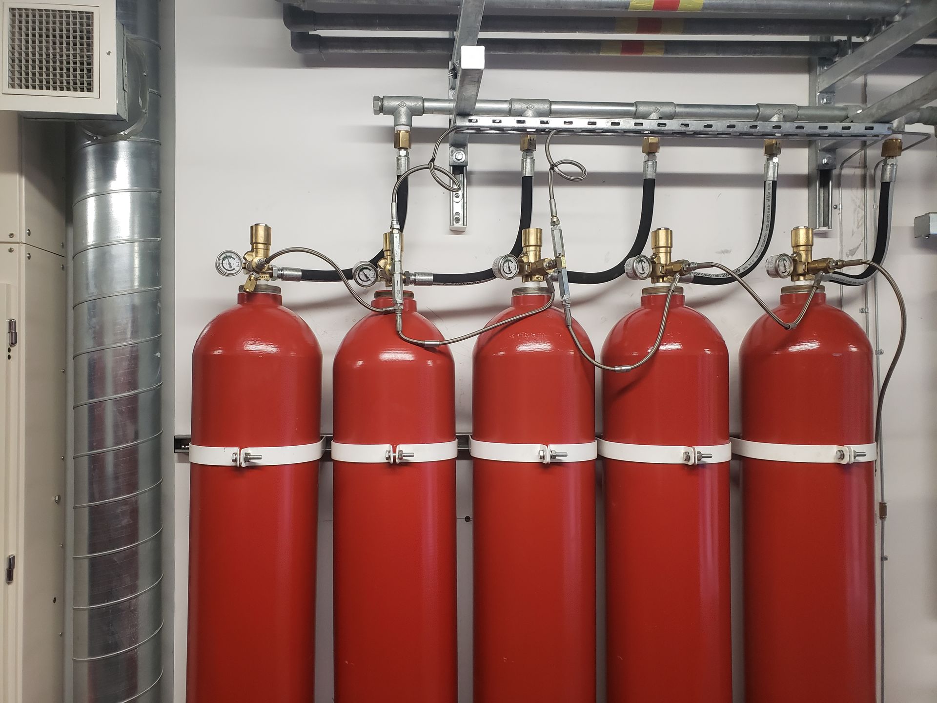 Four red gas cylinders are lined up in a room
