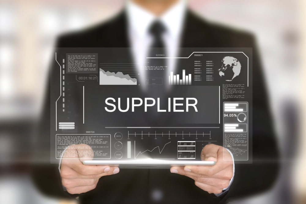 A man in a suit is holding a tablet with the word supplier on it.