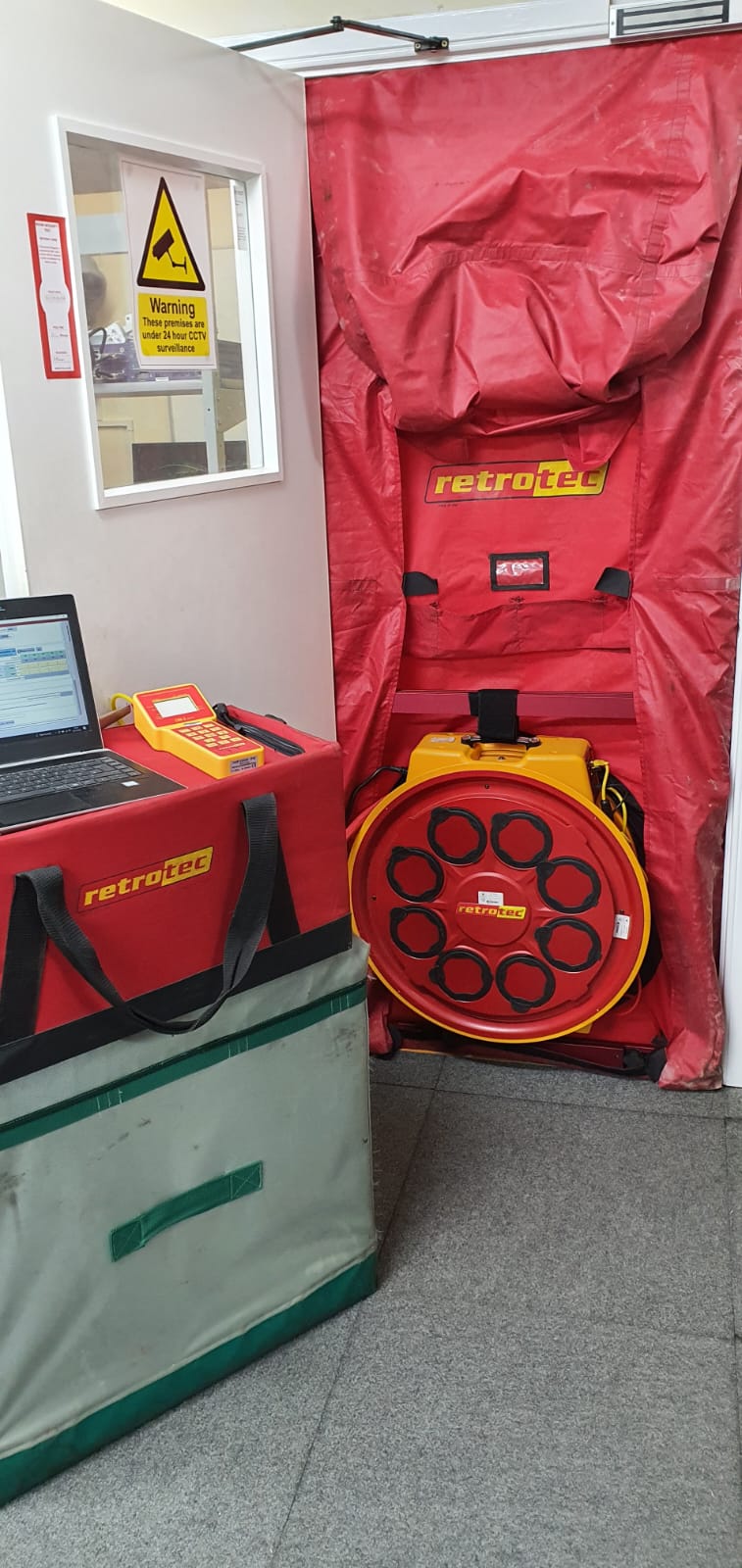A room with a red tarp covering a door and a laptop.