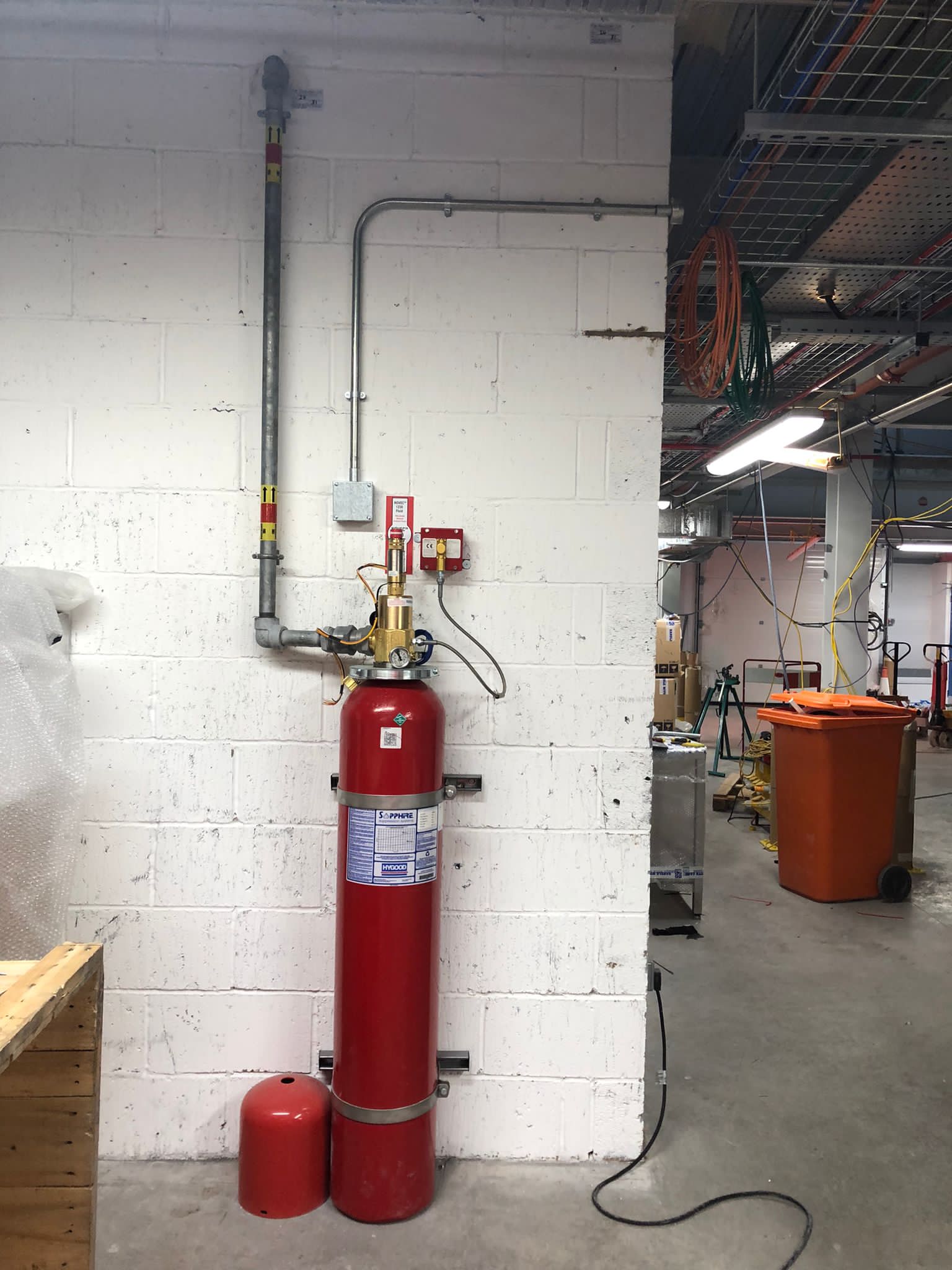 A red fire extinguisher is hanging on a white brick wall in a room.