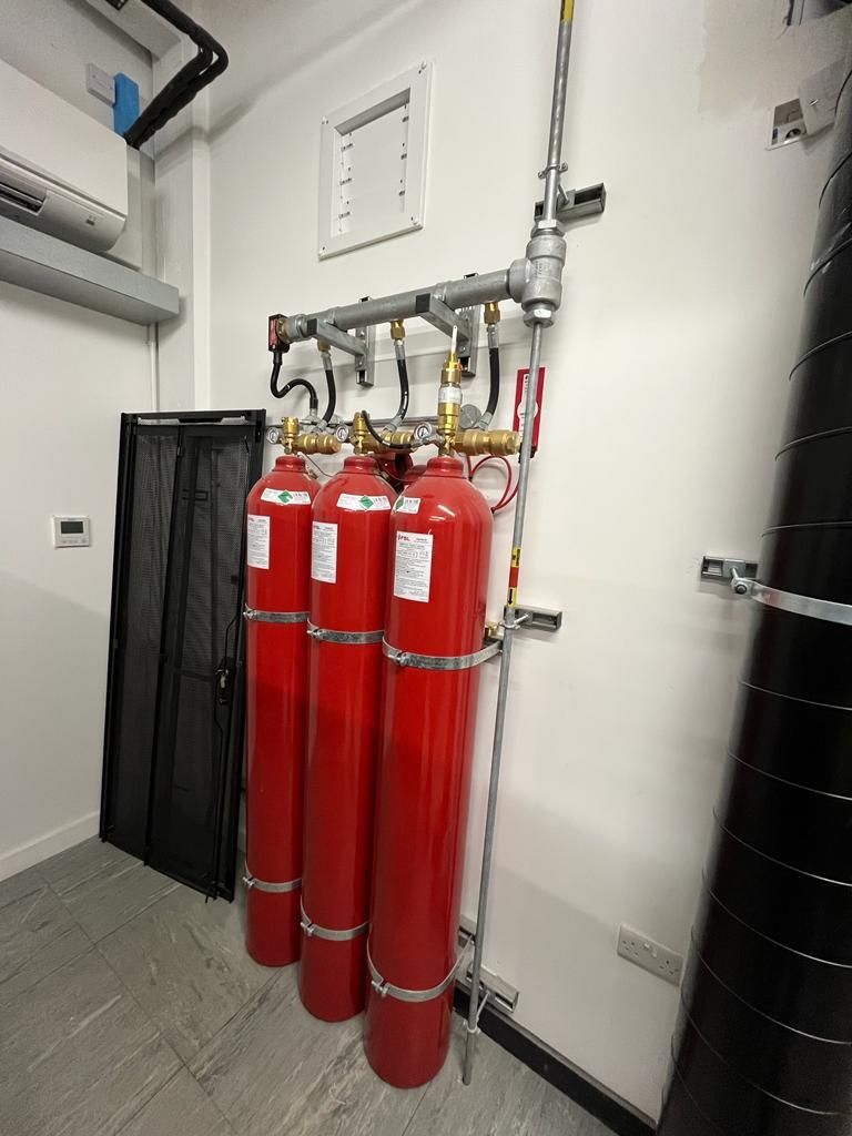 Three red gas cylinders are sitting next to each other in a room.