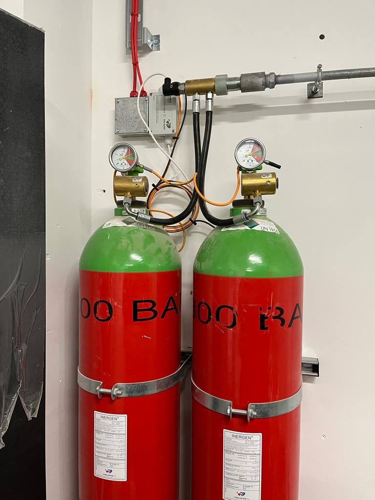 Two red and green gas cylinders are attached to a wall.