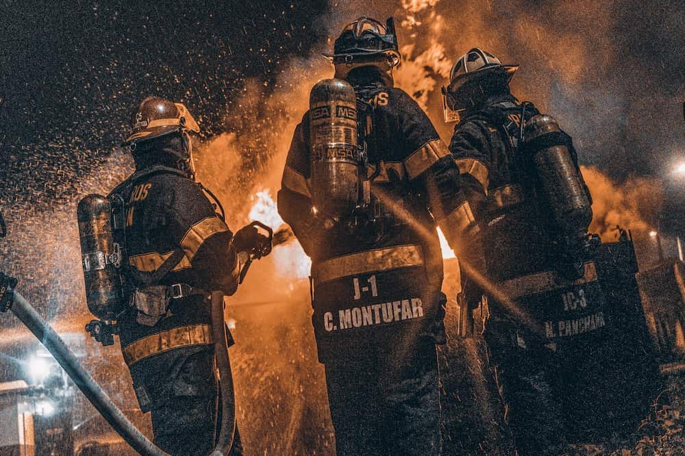 A group of firefighters are standing in front of a fire.