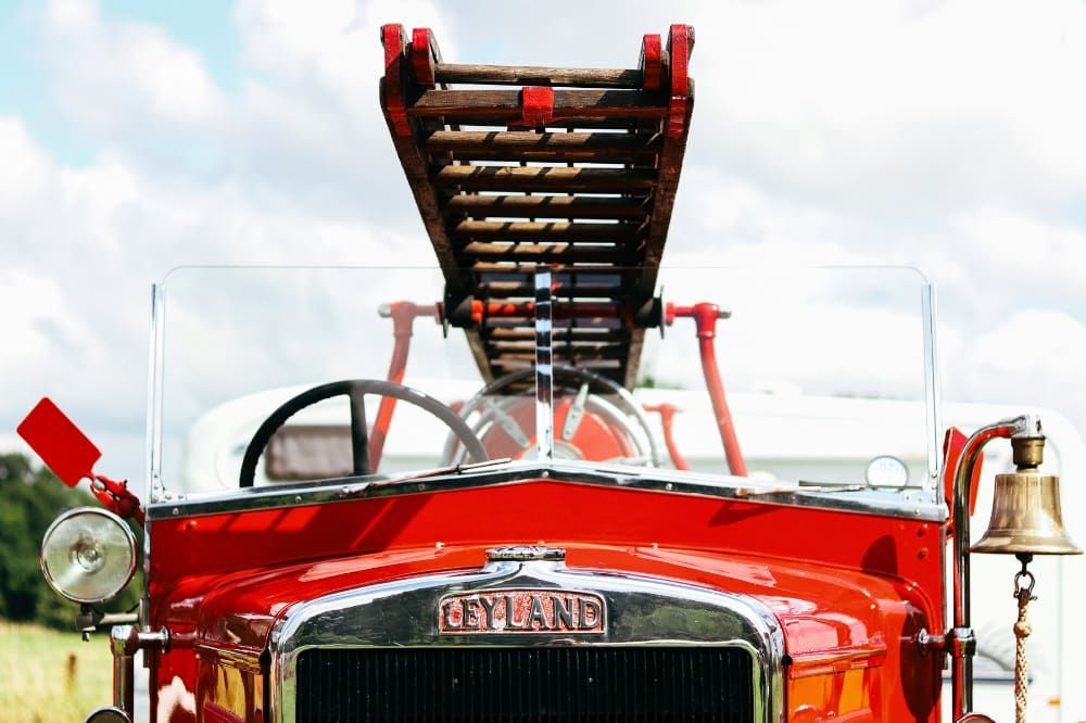 A red fire truck with a wooden ladder on top of it.