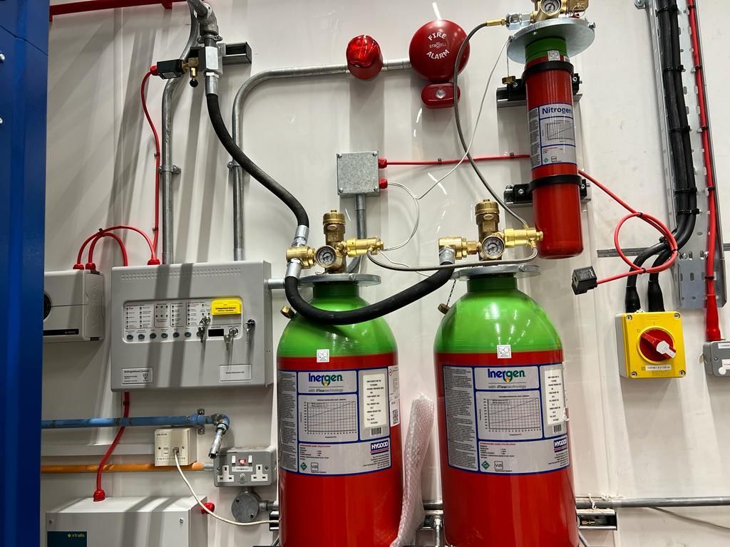 Two red and green fire extinguishers are hanging on a wall.