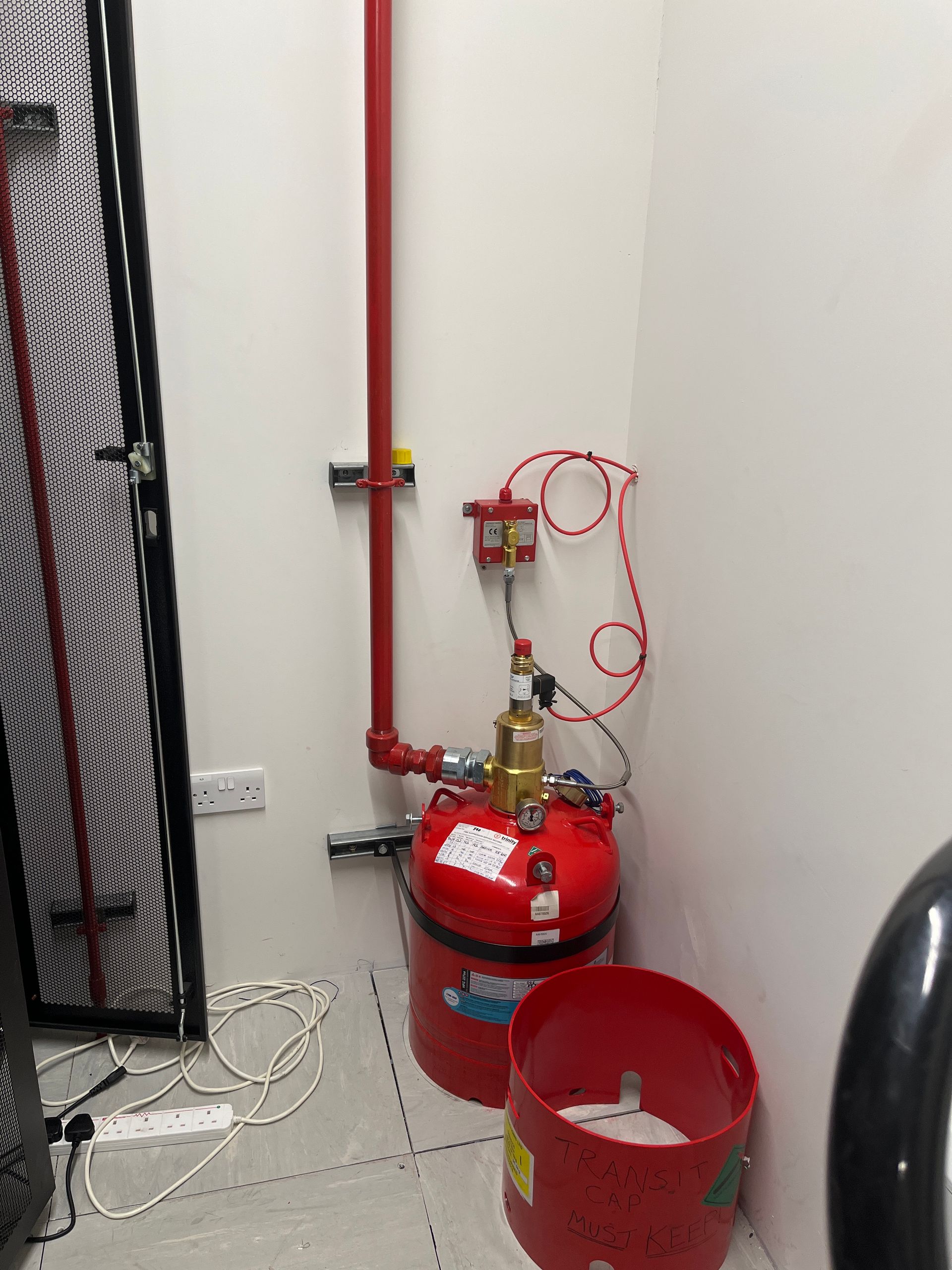 A red fire extinguisher is sitting in a corner of a room.