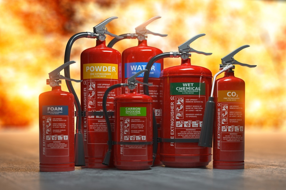 A group of fire extinguishers are sitting on a table in front of a fire.