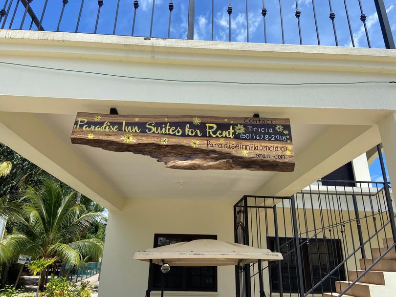 A sign on the side of a building that says paradise inn suites for rent