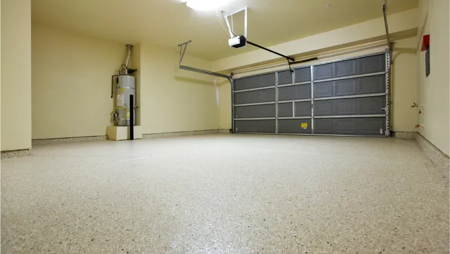 Empty two-car garage with gray door, beige walls, and speckled concrete floor.