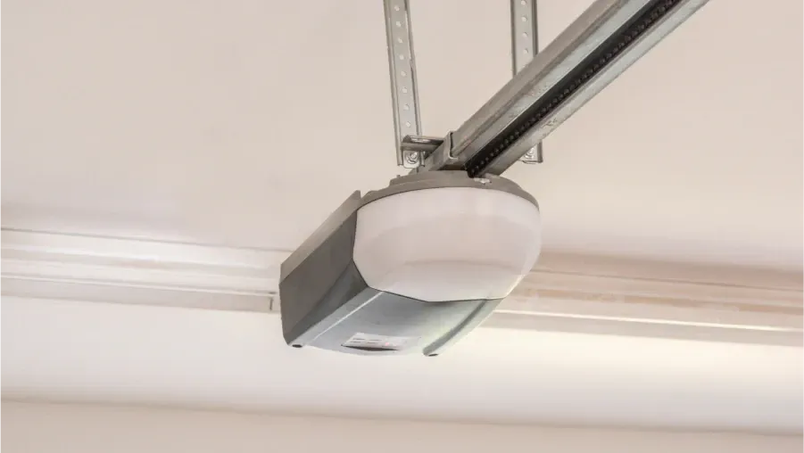 Garage door opener mounted on a ceiling track with a round white light cover