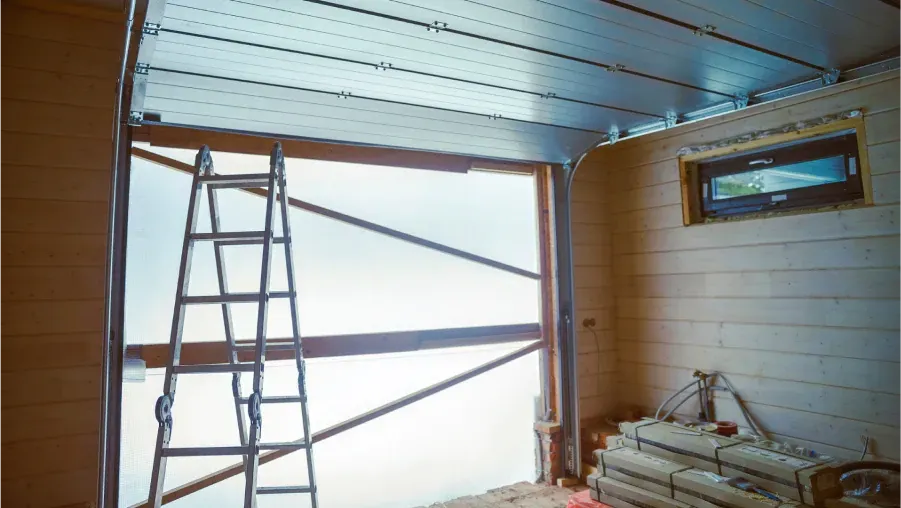 Ladder in a partially renovated room with exposed framing, wood paneling, and construction materials.