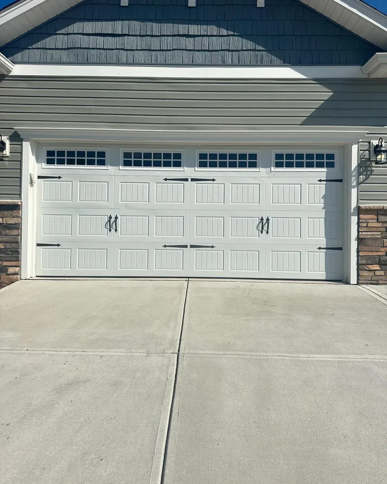 White double garage door on a suburban house with a concrete driveway and stone accents