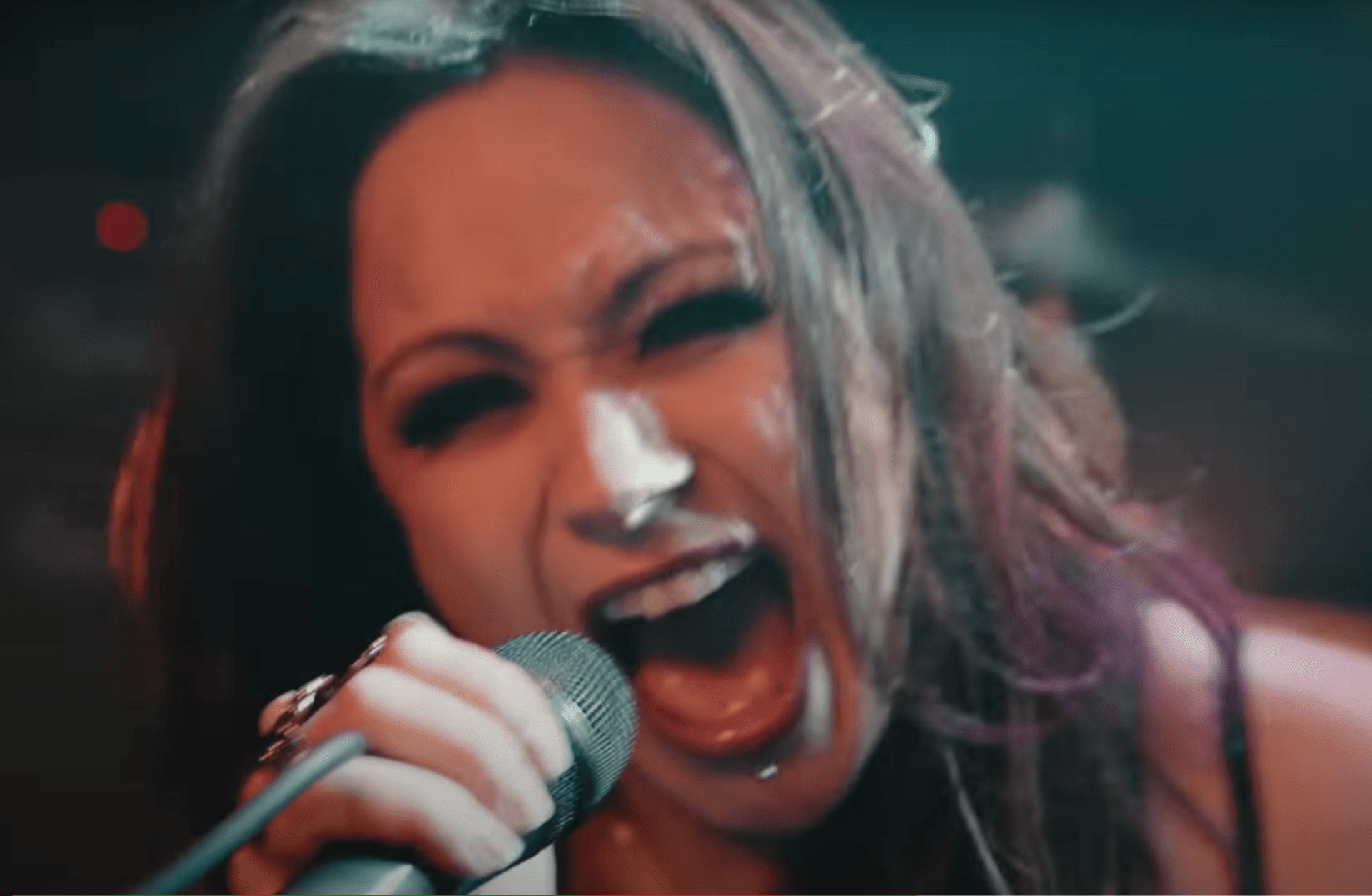 Passionate rock chick singing with a magenta-lit microphone on stage