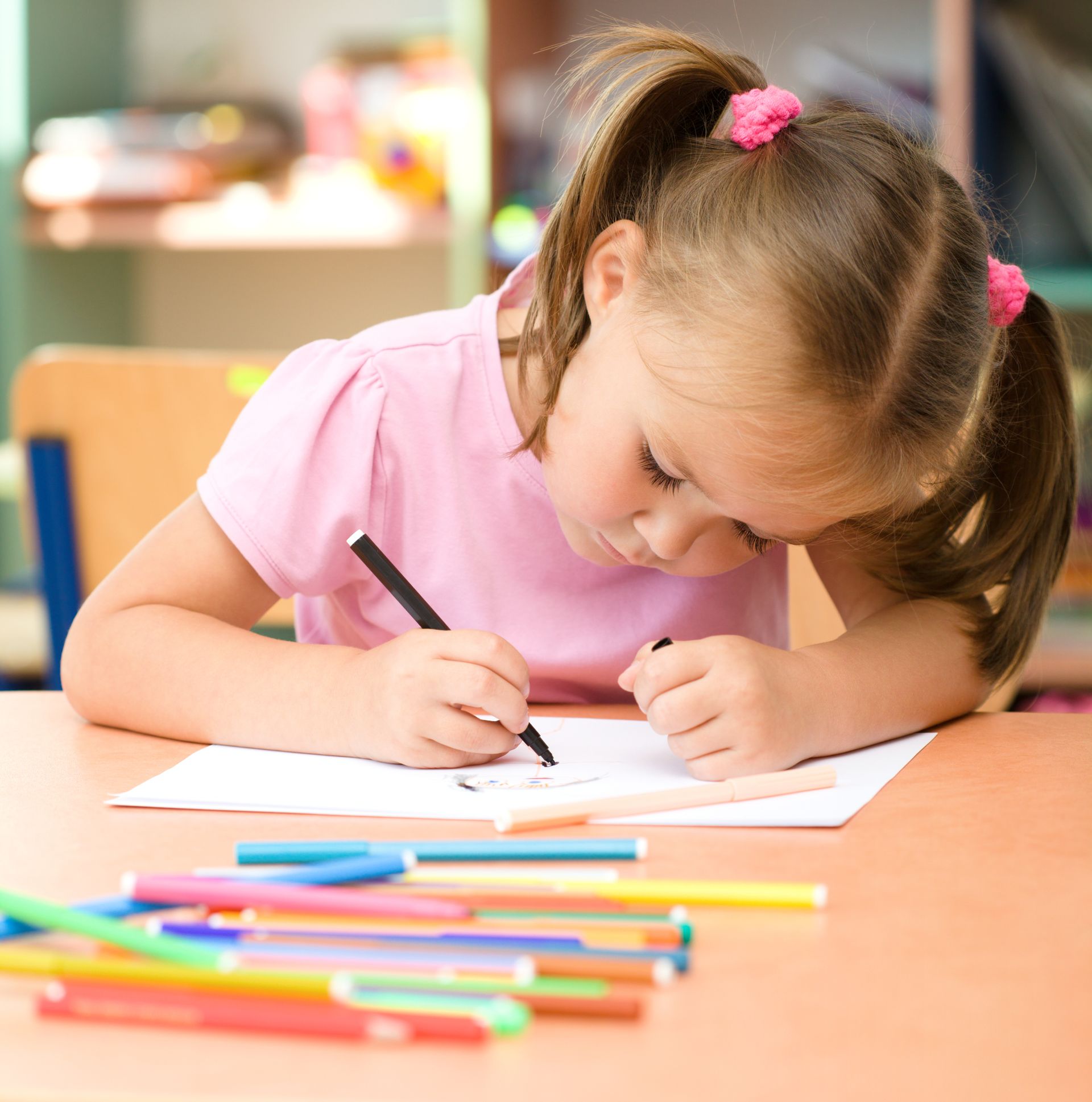 Cute little girl is drawing with felt-tip pen in preschool.