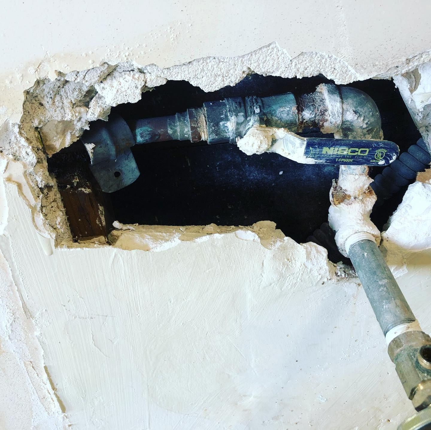 A pipe is coming out of a hole in the wall.