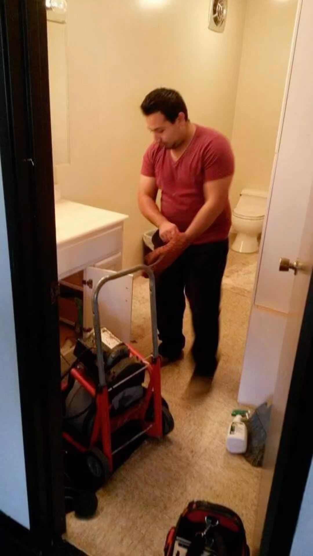 A man is working on a pipe in a bathroom.