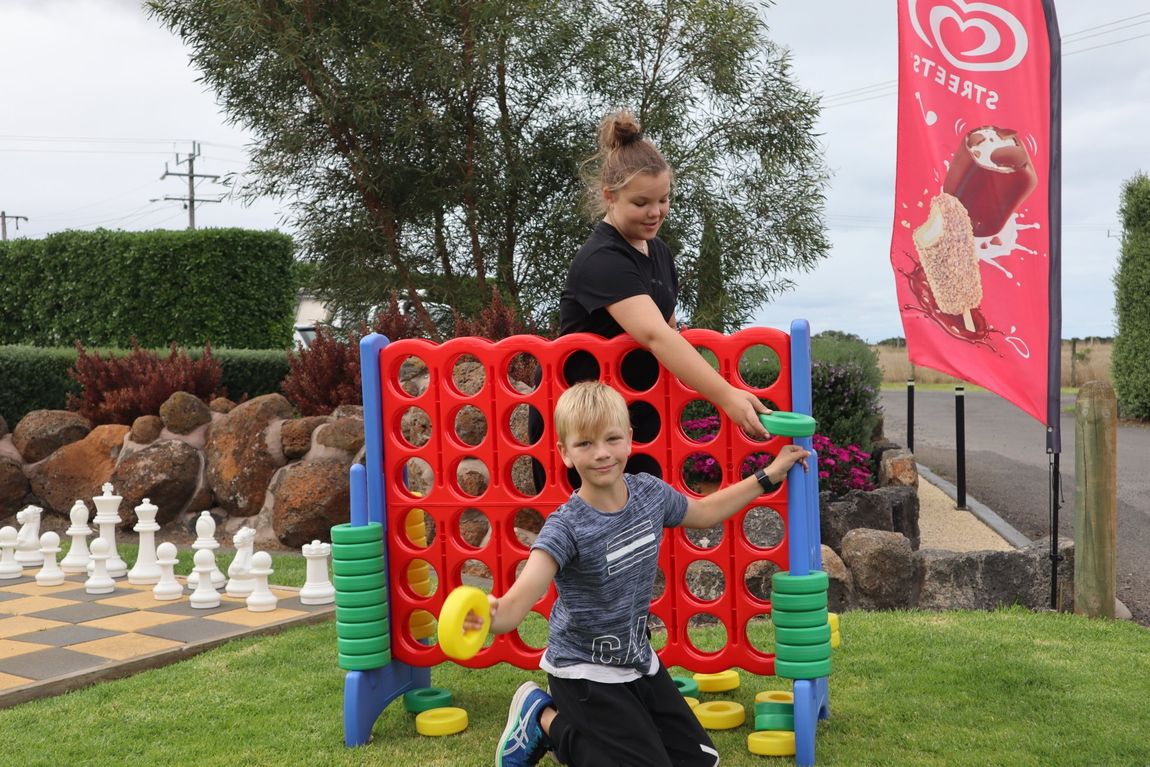 Girl and boy play with a giant connect-four set at Gum Tree Caravan Park