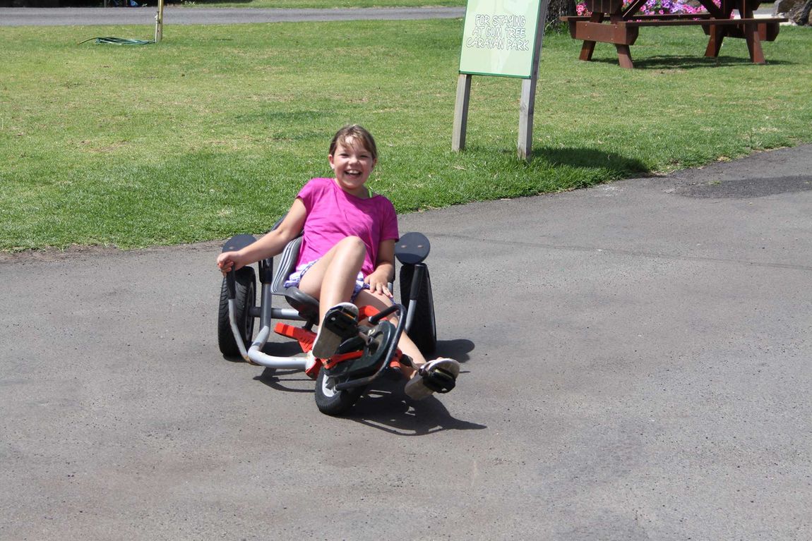 Girl laughing and riding a tricycle at Gum Tree Caravan Park
