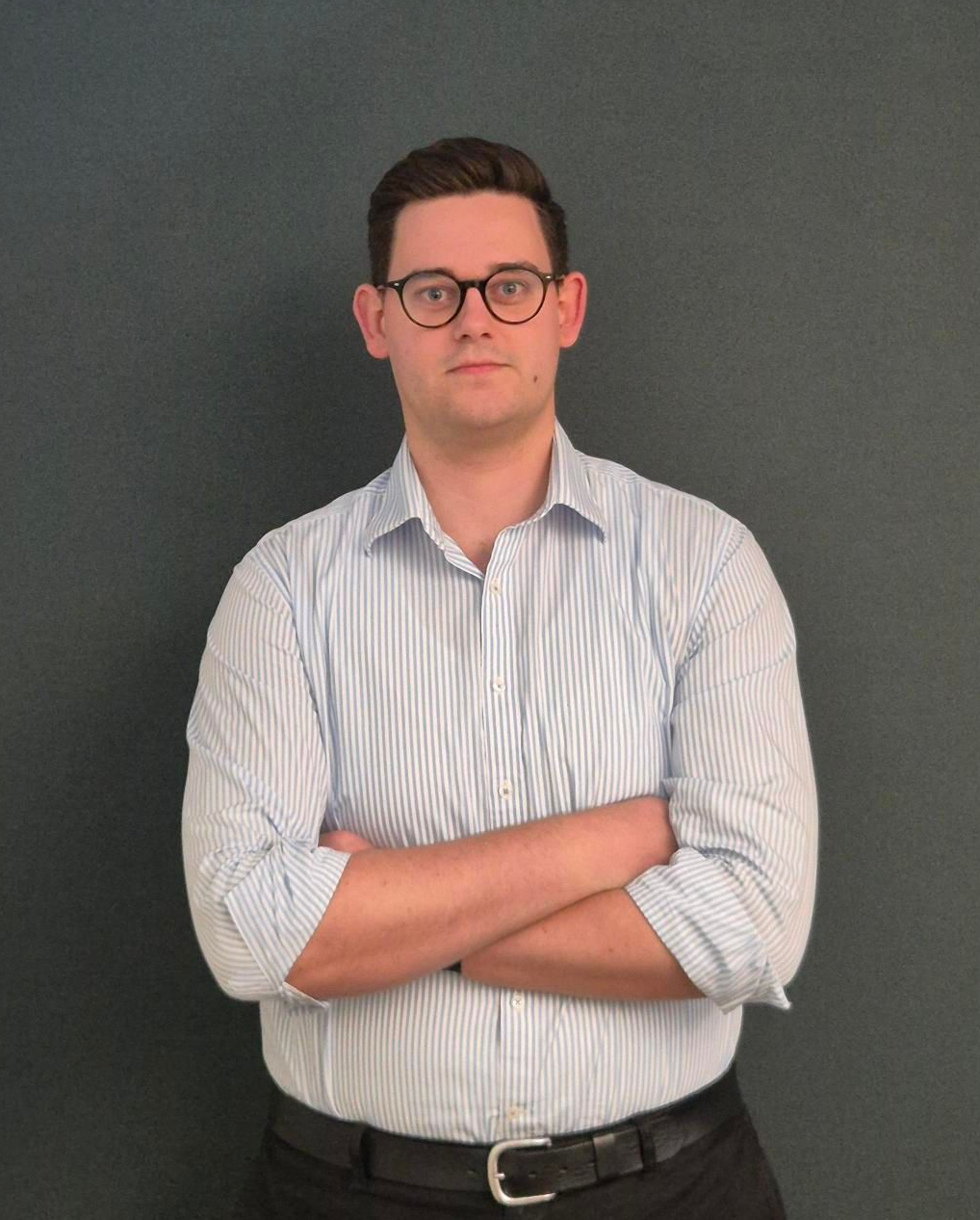 Man in a warehouse, using a tablet, surrounded by boxes on shelves.
