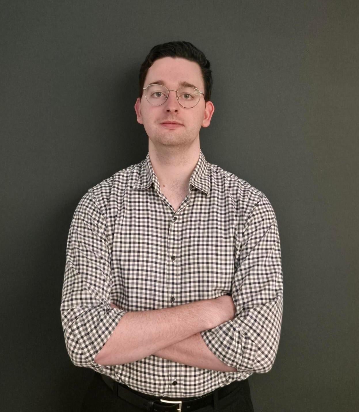 Man in blue shirt smiles in office setting, natural light.
