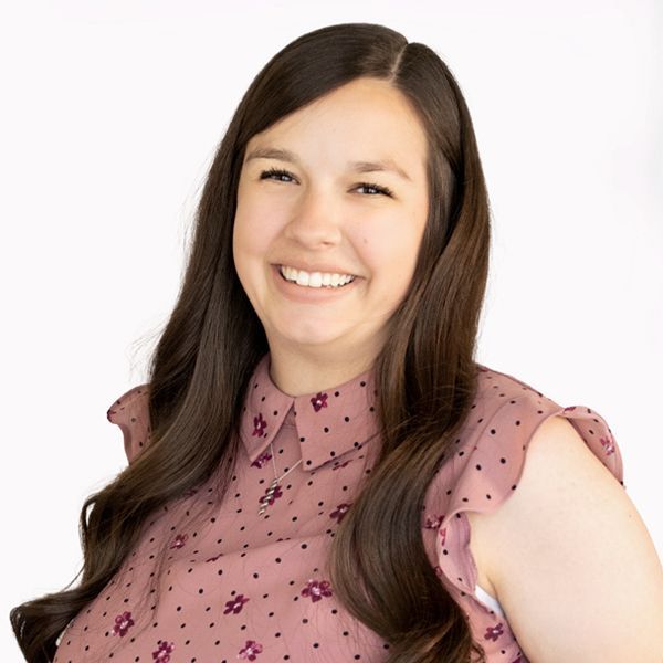 A woman in a white tank top is smiling for the camera.