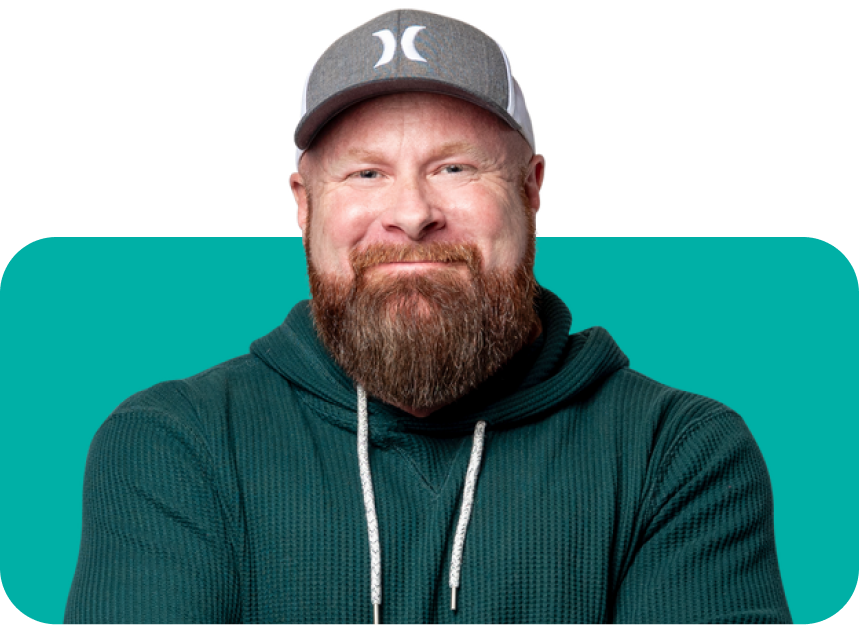 A man with a beard is wearing a hat and a green hoodie.