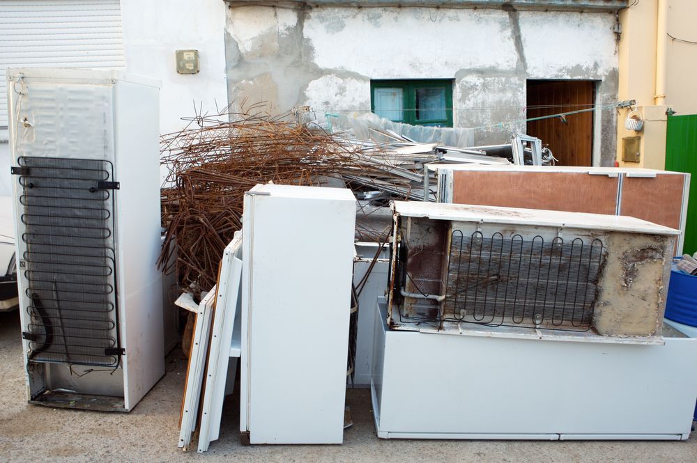 A pile of old appliances is sitting in front of a building.