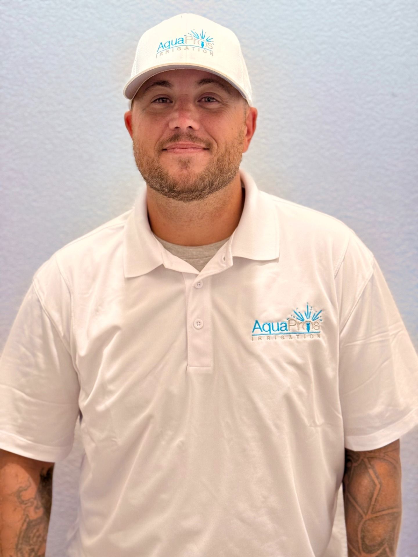 A man with a beard is holding a wrench and smiling.