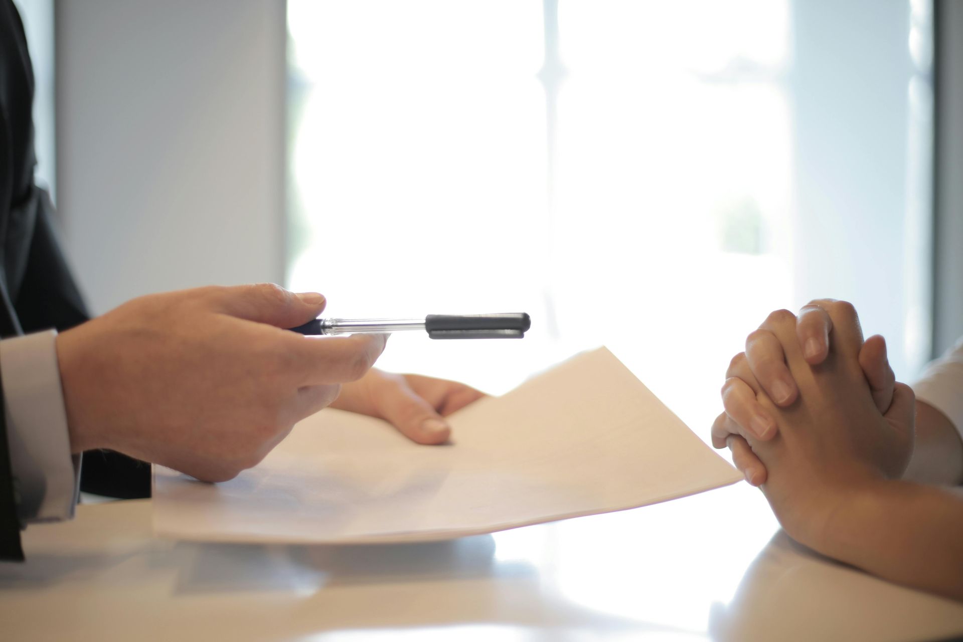 A man is giving an insurance policy to a woman to sign.