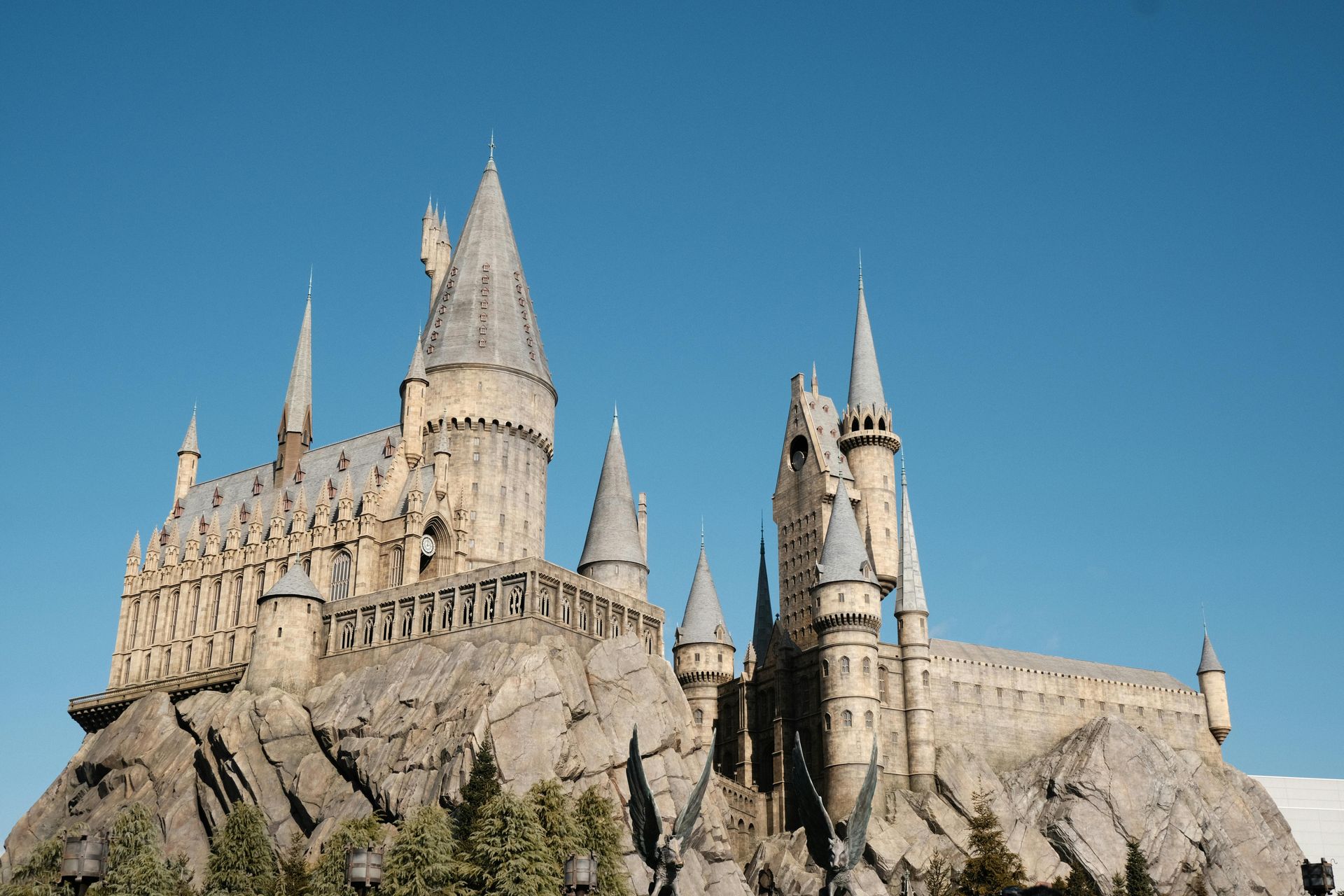 A wide shot of Hogwarts Castle perched on a rocky cliff under a clear blue sky.