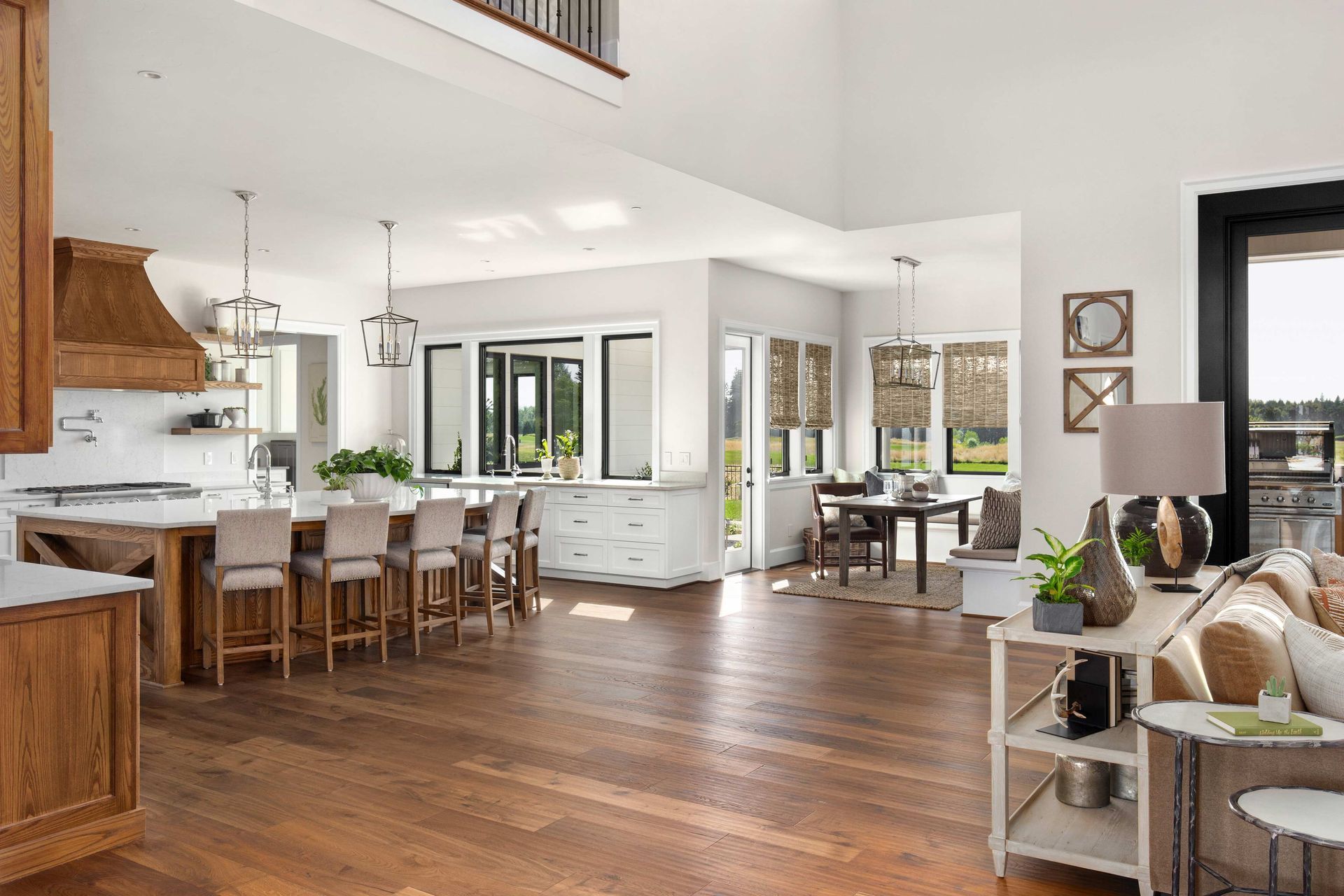 Bright open-concept kitchen and living room with hardwood floors, white cabinets, and large windows